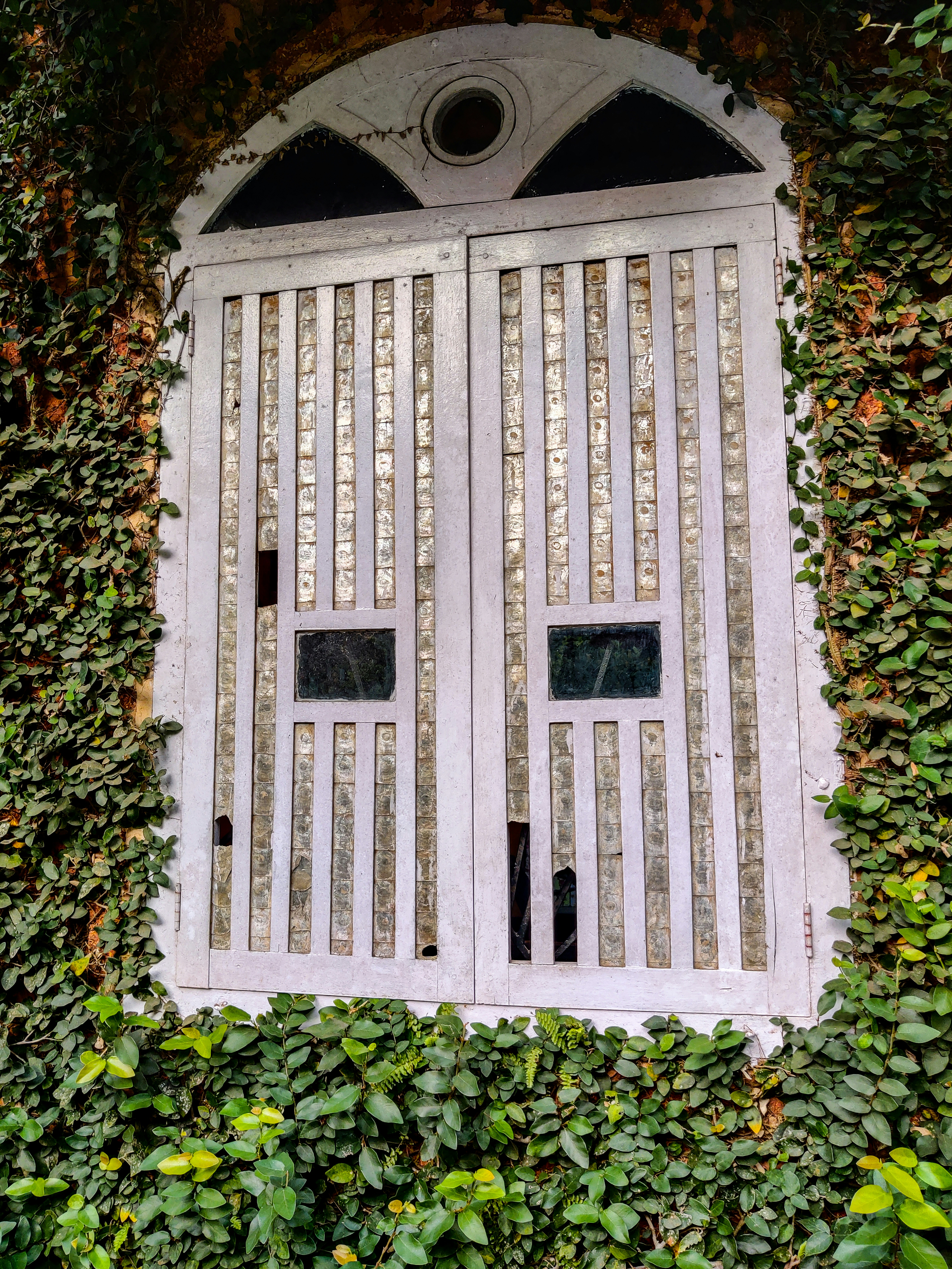 a window in the side of a building covered in ivy