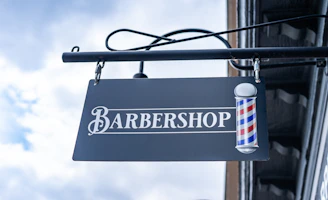 A polished gold and black sign displaying the alpha studio logo hanging inside the stylish barber shop.