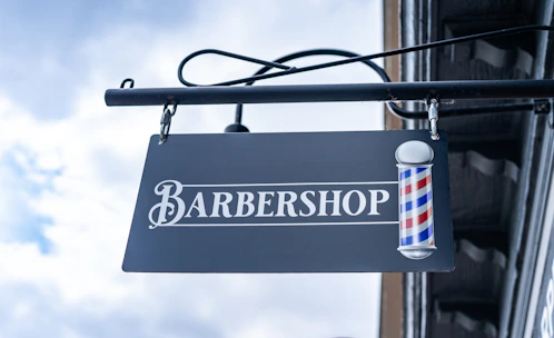 A polished gold and black sign displaying the alpha studio logo hanging inside the stylish barber shop.