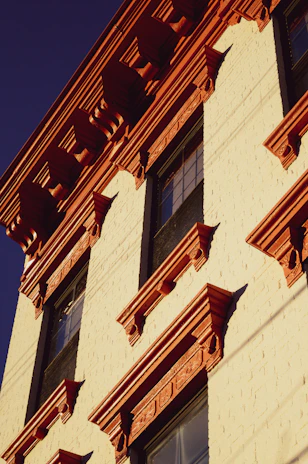 Exterior house facade showcasing expert paintwork and decorative plaster details under natural sunlight.