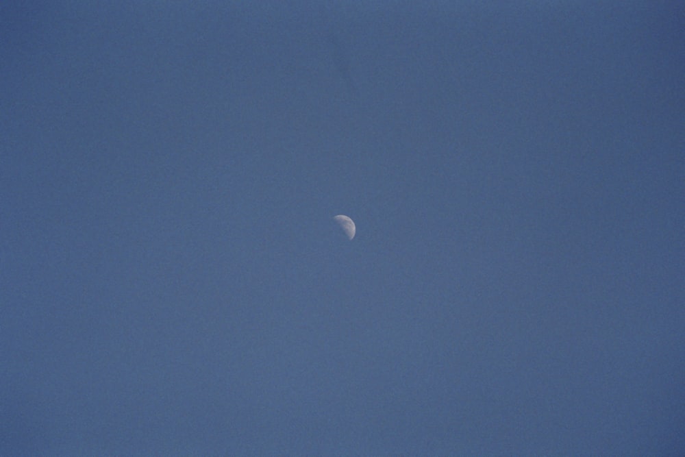 a plane flying in the sky with the moon in the distance