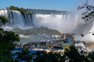 A vibrant photo of tourists enjoying the breathtaking Iguazu Falls with lush greenery around.