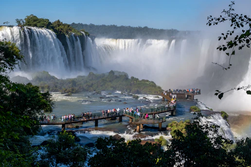 A vibrant photo of tourists enjoying the breathtaking Iguazu Falls with lush greenery around.