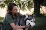 Woman gently guiding her Siberian husky through an indoor brain game on a bright morning.