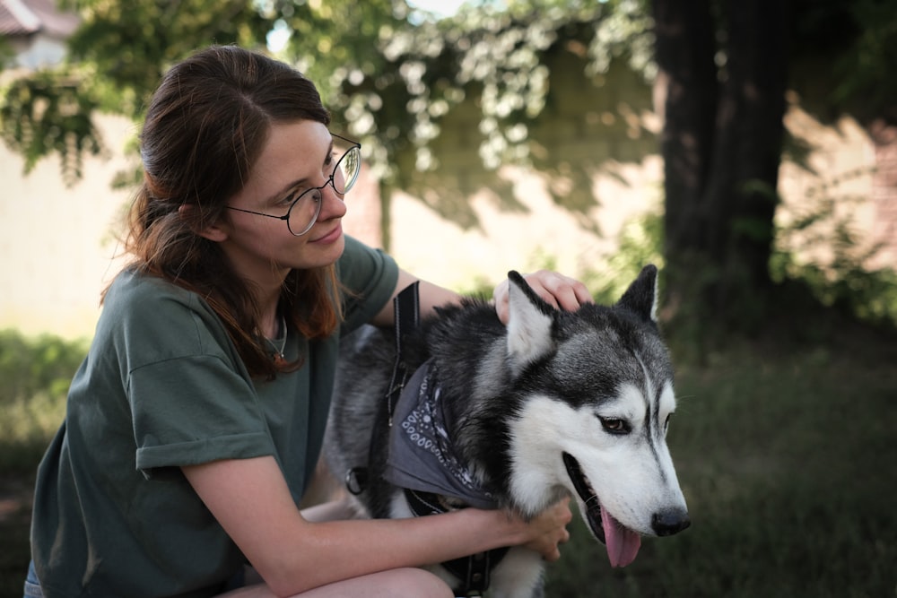 a woman in glasses petting a husky dog
