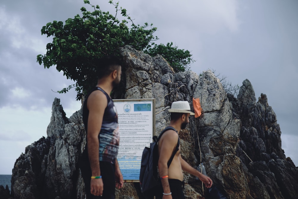 um casal de homens ao lado de uma placa