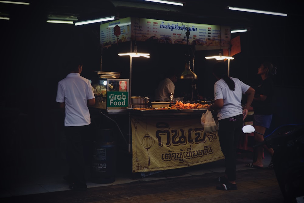 a group of people standing around a food stand