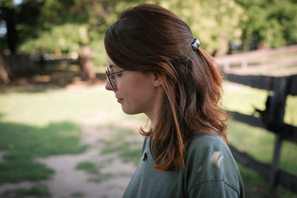 a woman with glasses standing in front of a fence