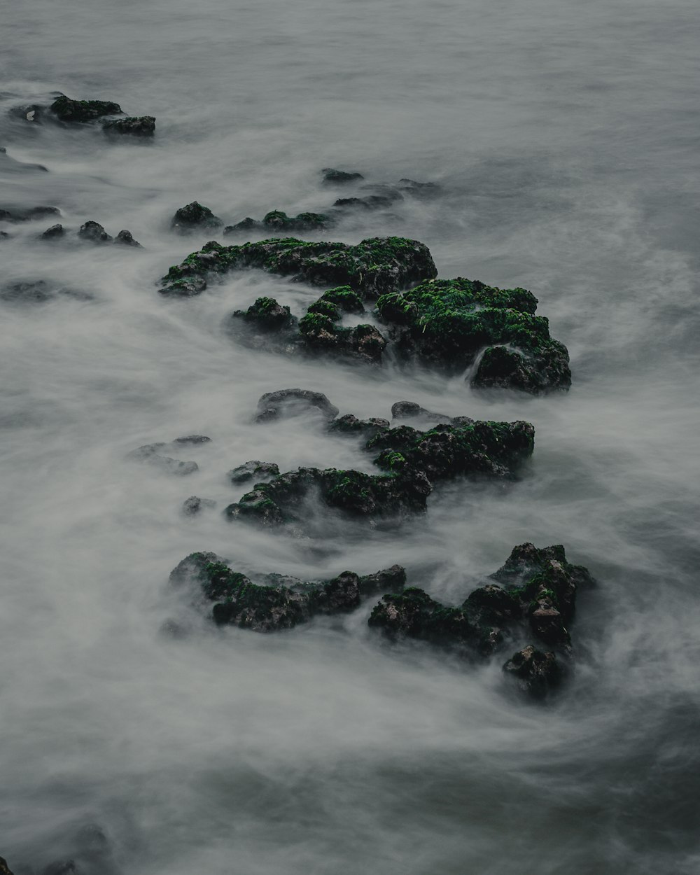 a long exposure photo of rocks in the water