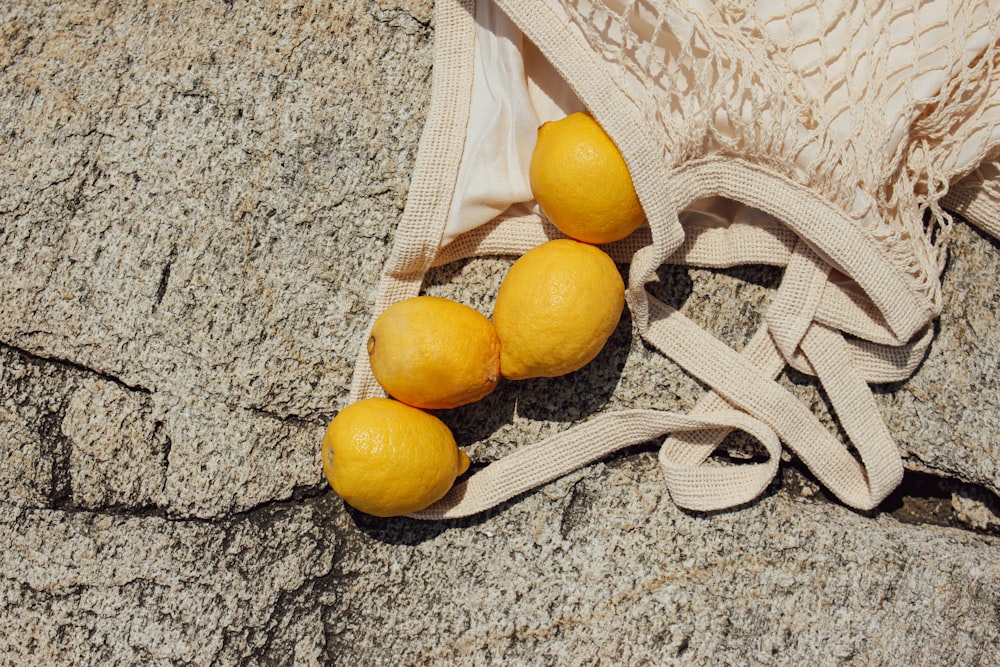 three lemons sitting on top of a cloth bag
