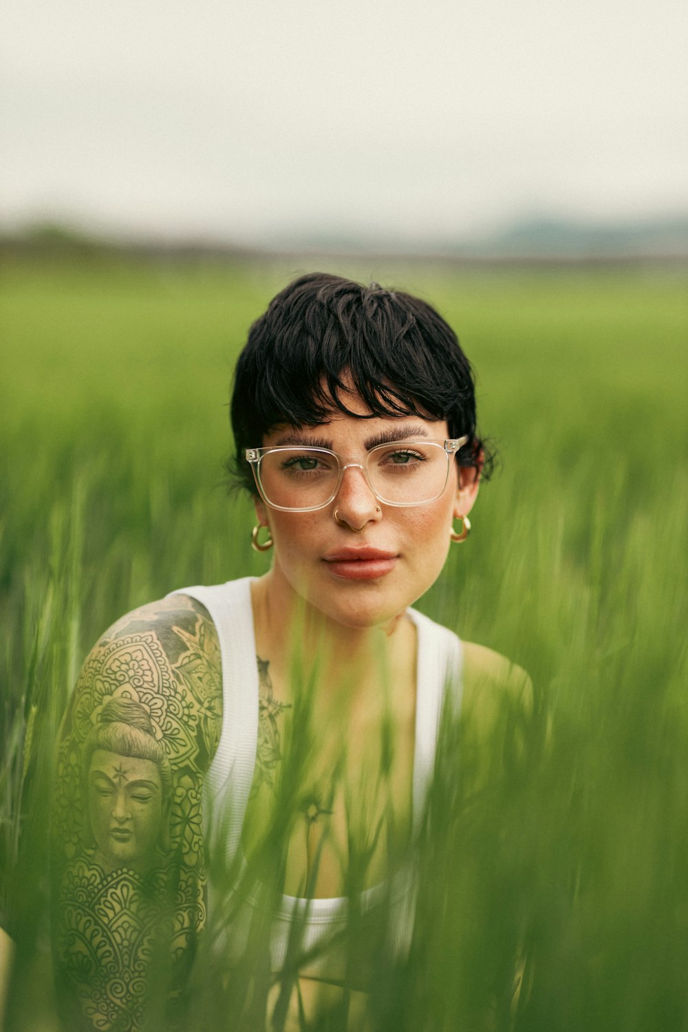 a woman wearing glasses in a field of tall grass