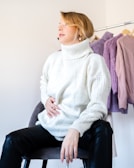 A model seated gracefully wearing a soft pastel knit sweater and relaxed-fit pants.
