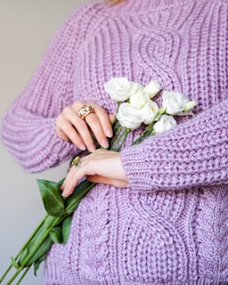 a woman in a purple sweater holding a bouquet of flowers