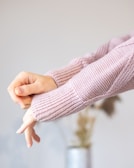 Close-up of hands adjusting a dusky pink lightweight sweater.