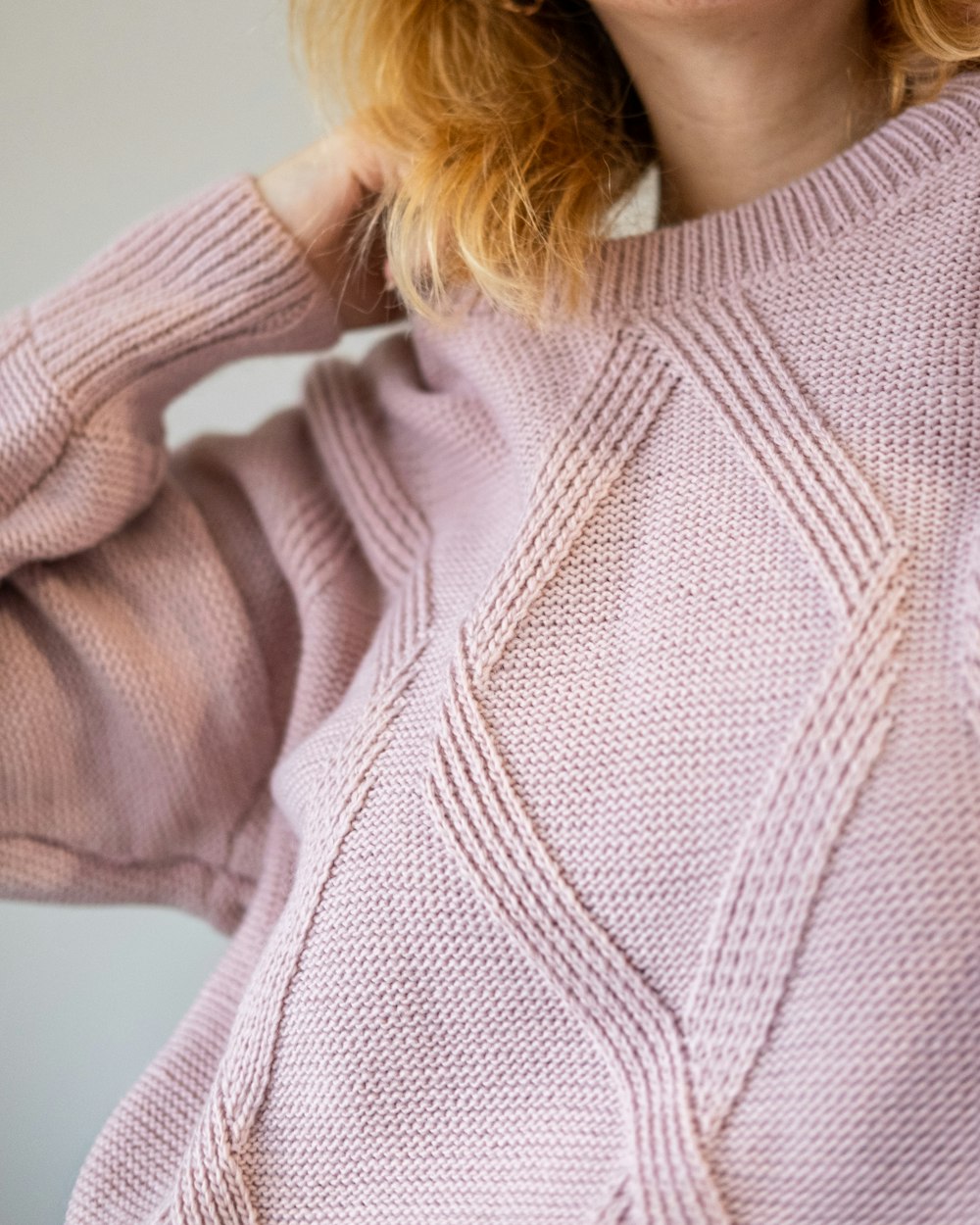 a woman with red hair wearing a pink sweater