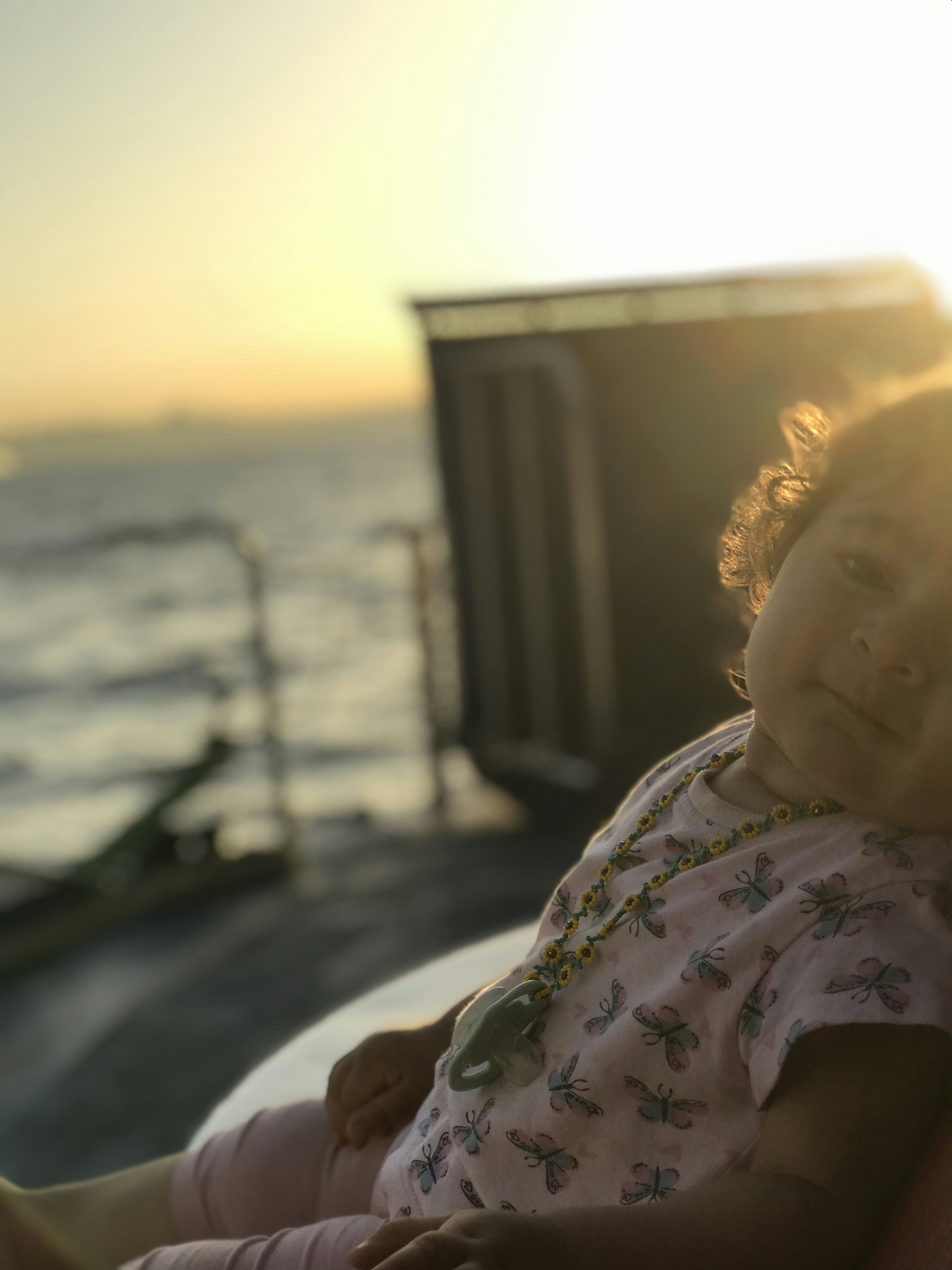 a little girl sitting on top of a couch next to the ocean