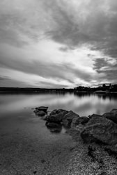 An elegant black-and-white shot of a serene lake reflecting ancient stone ruins.