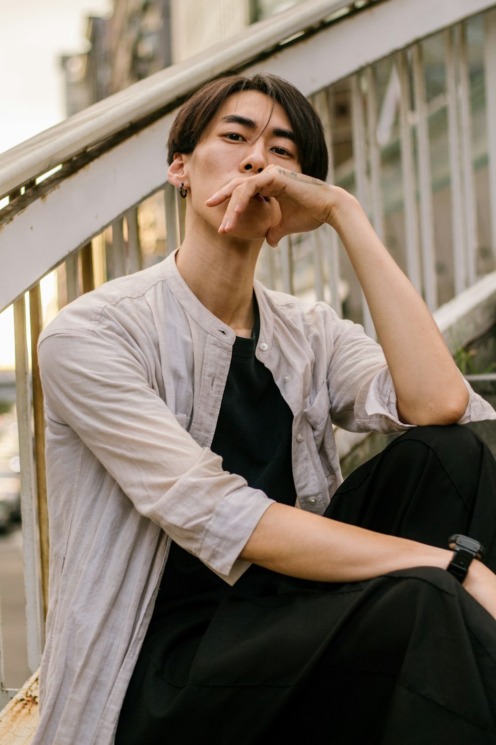 a man sitting on a ledge with his hand on his mouth