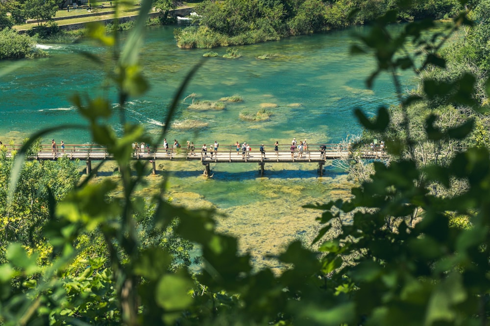 eine gruppe von menschen, die über eine brücke über einen fluss gehen