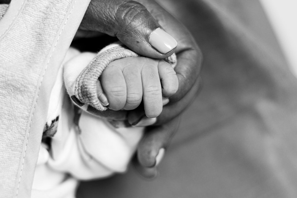 a black and white photo of a person holding a baby