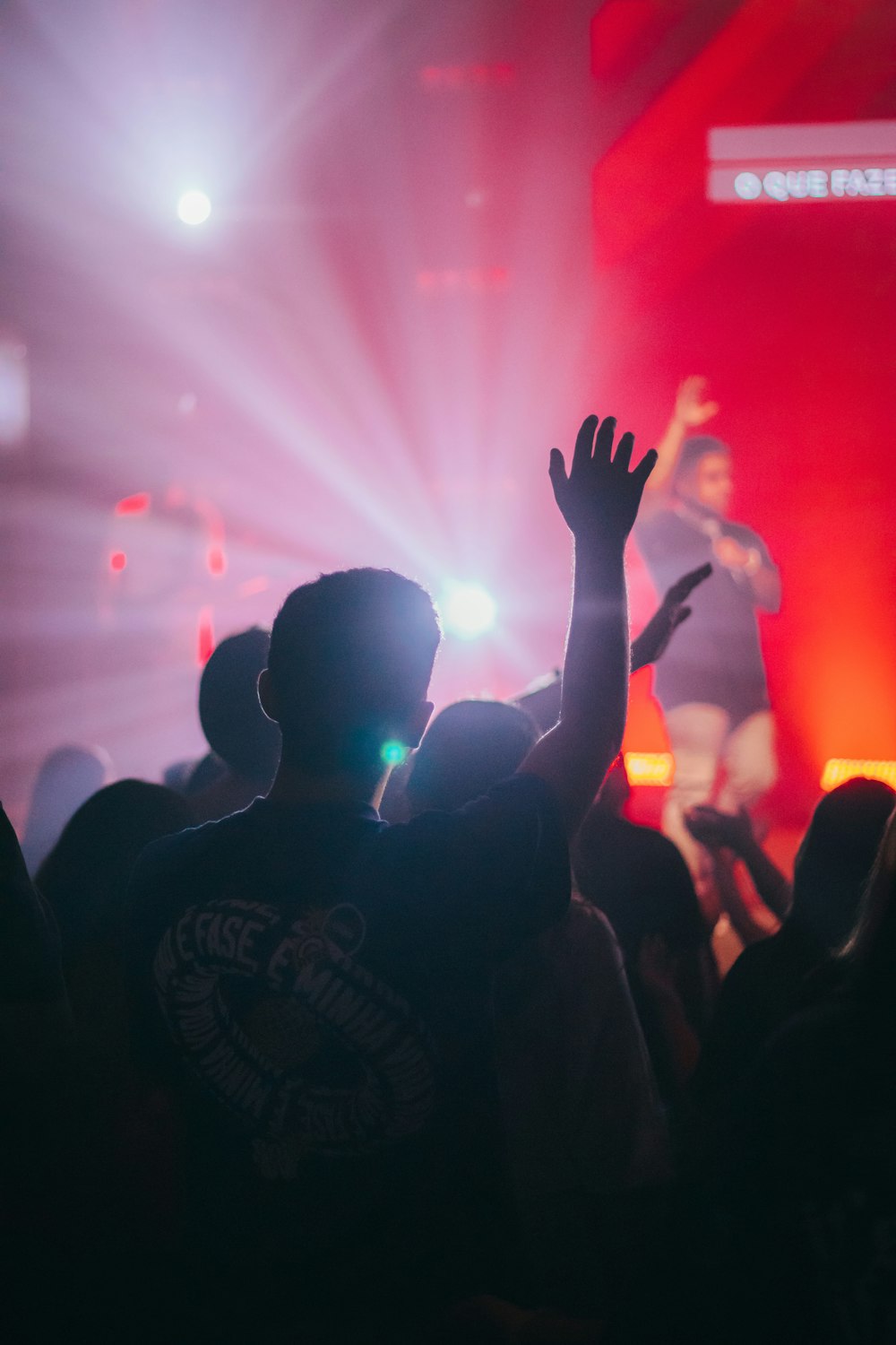 a crowd of people at a concert with their hands in the air