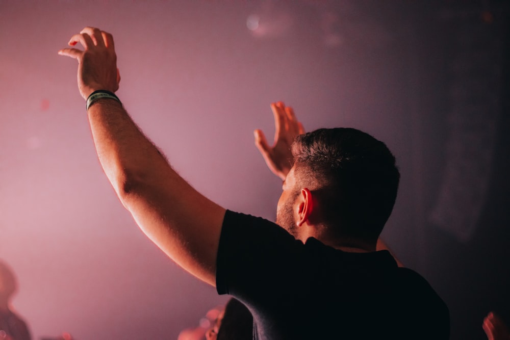 a man standing in front of a crowd holding his hands up