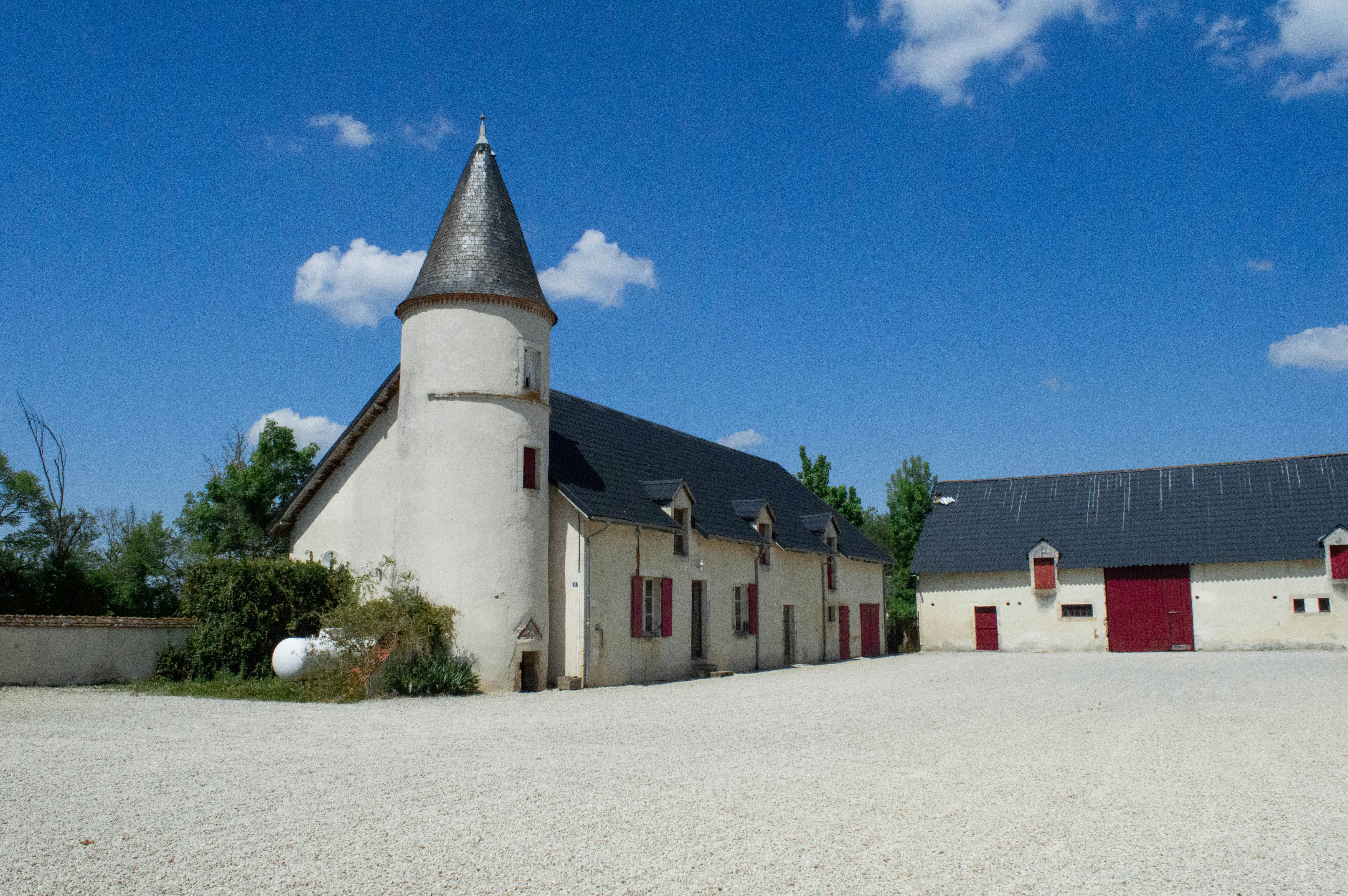 a white building with a black roof and a red door