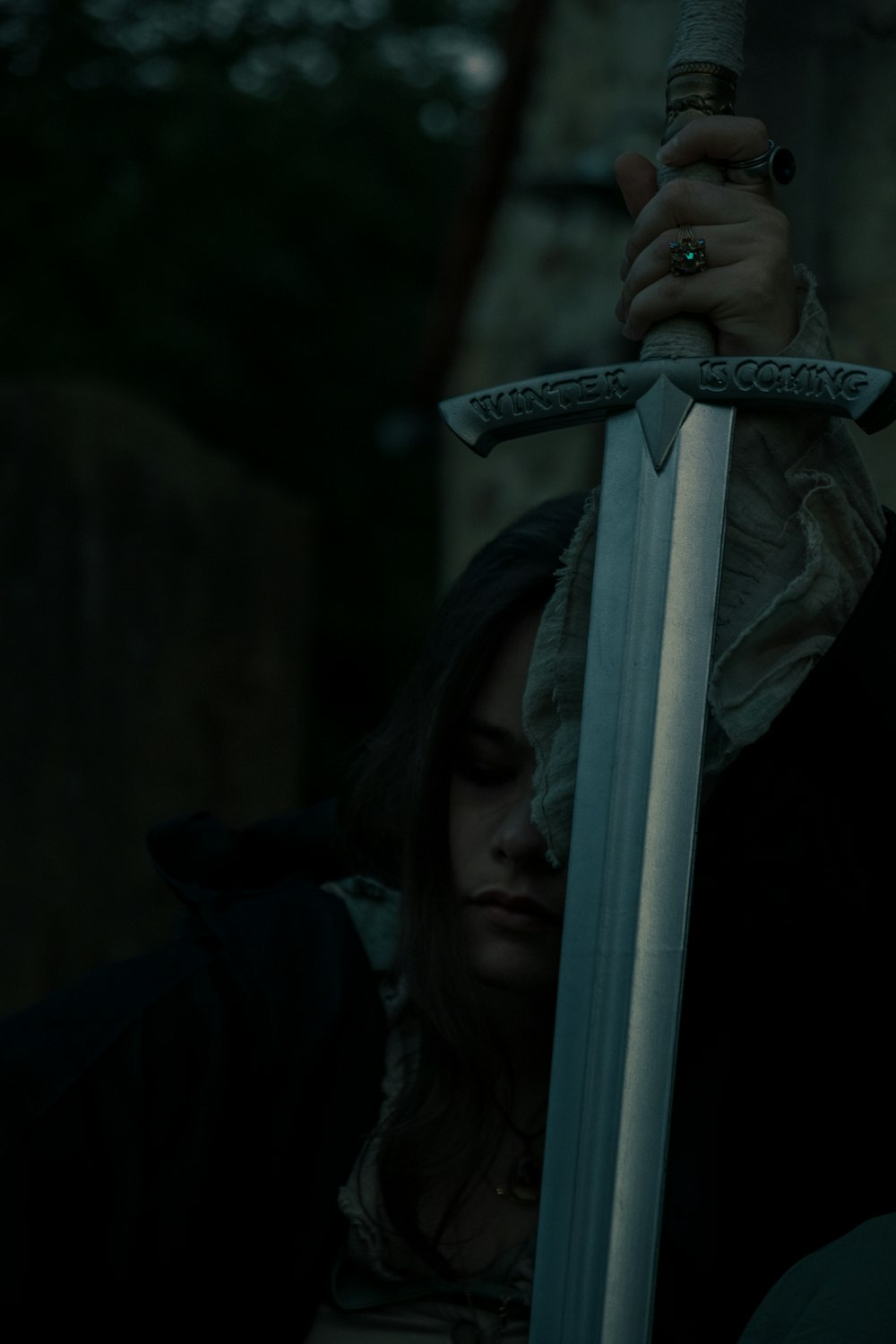 a woman holding a sword in a dark forest