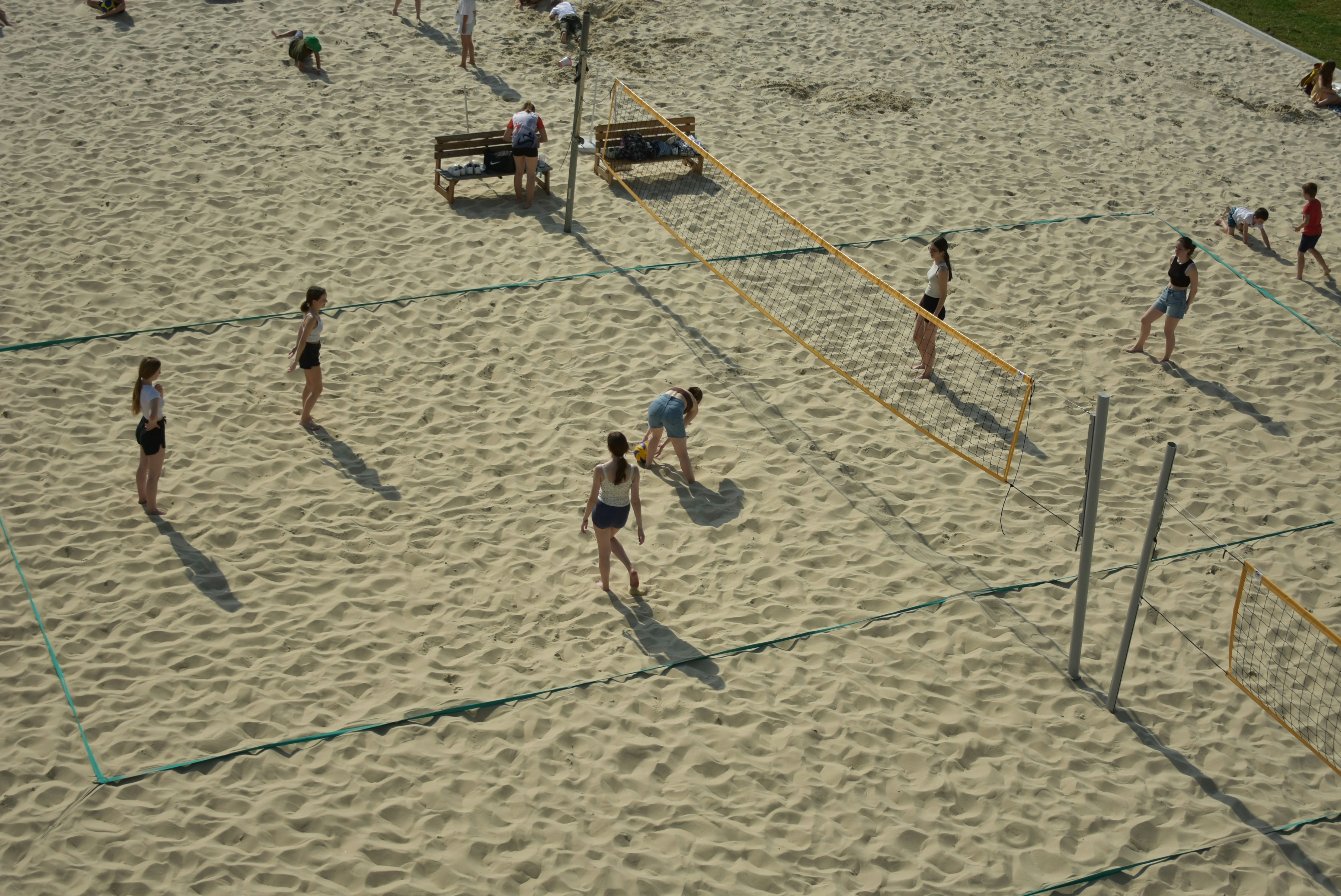 a group of people playing volleyball on a sandy beach