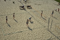 A volleyball team celebrating a point with high-fives on a sandy beach court.