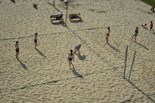 Children playing volleyball on a sandy court with colorful nets and lively energy.