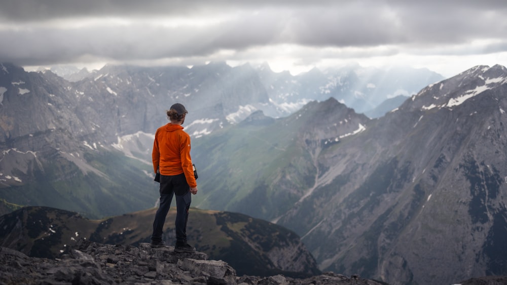 a man standing on top of a mountain looking at the mountains