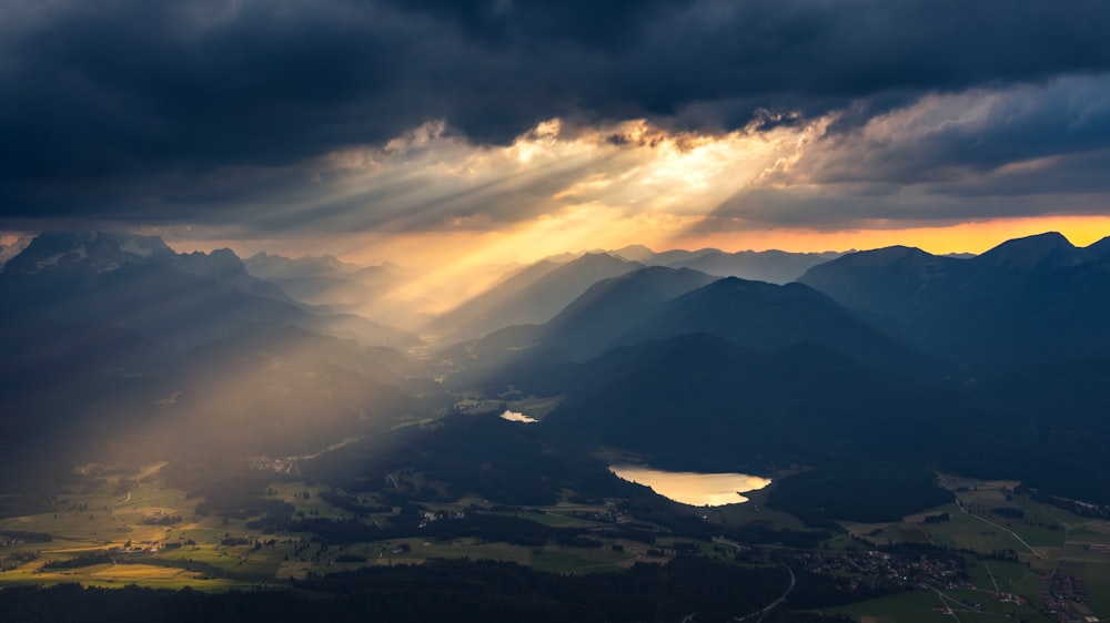 the sun is shining through the clouds over the mountains