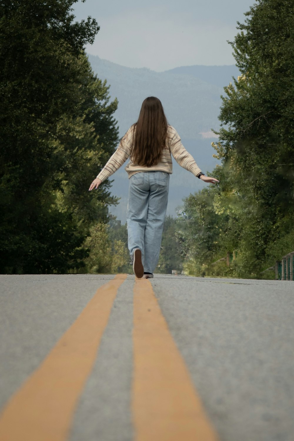 a woman walking down a road with her arms outstretched