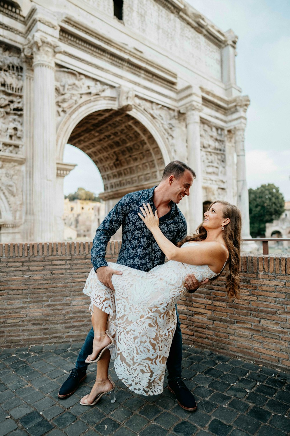 a man holding a woman in front of an arch of triumph