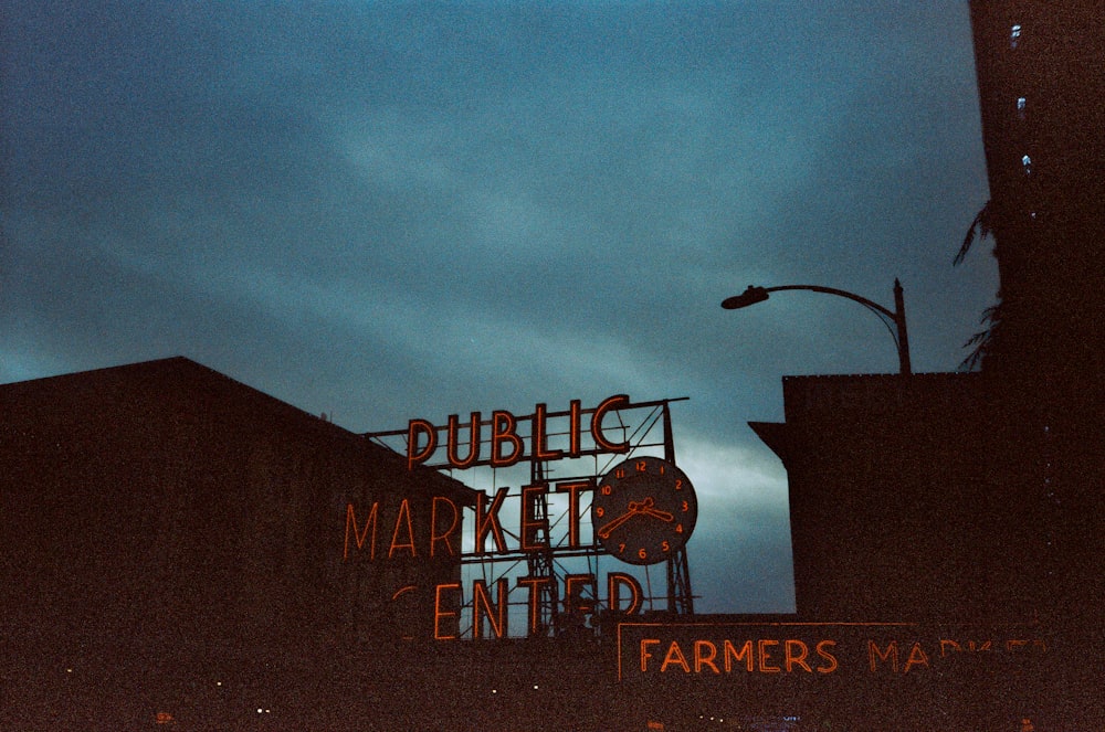 a sign for a farmers market is lit up at night