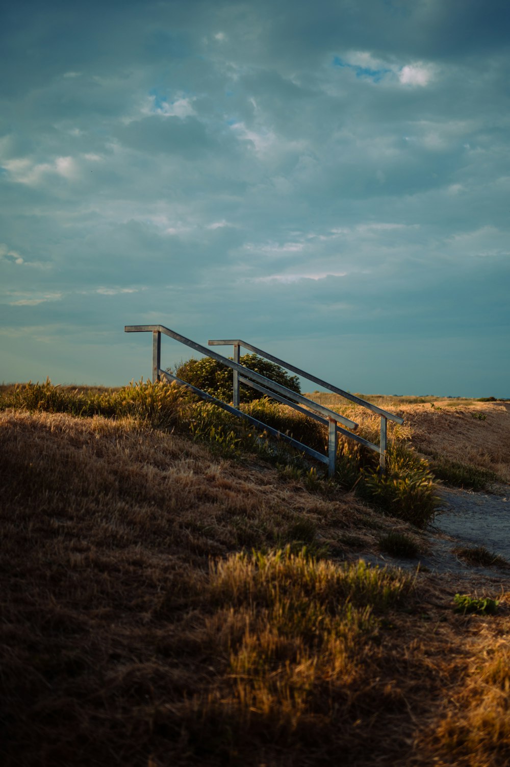 a metal fence sitting on top of a dry grass field