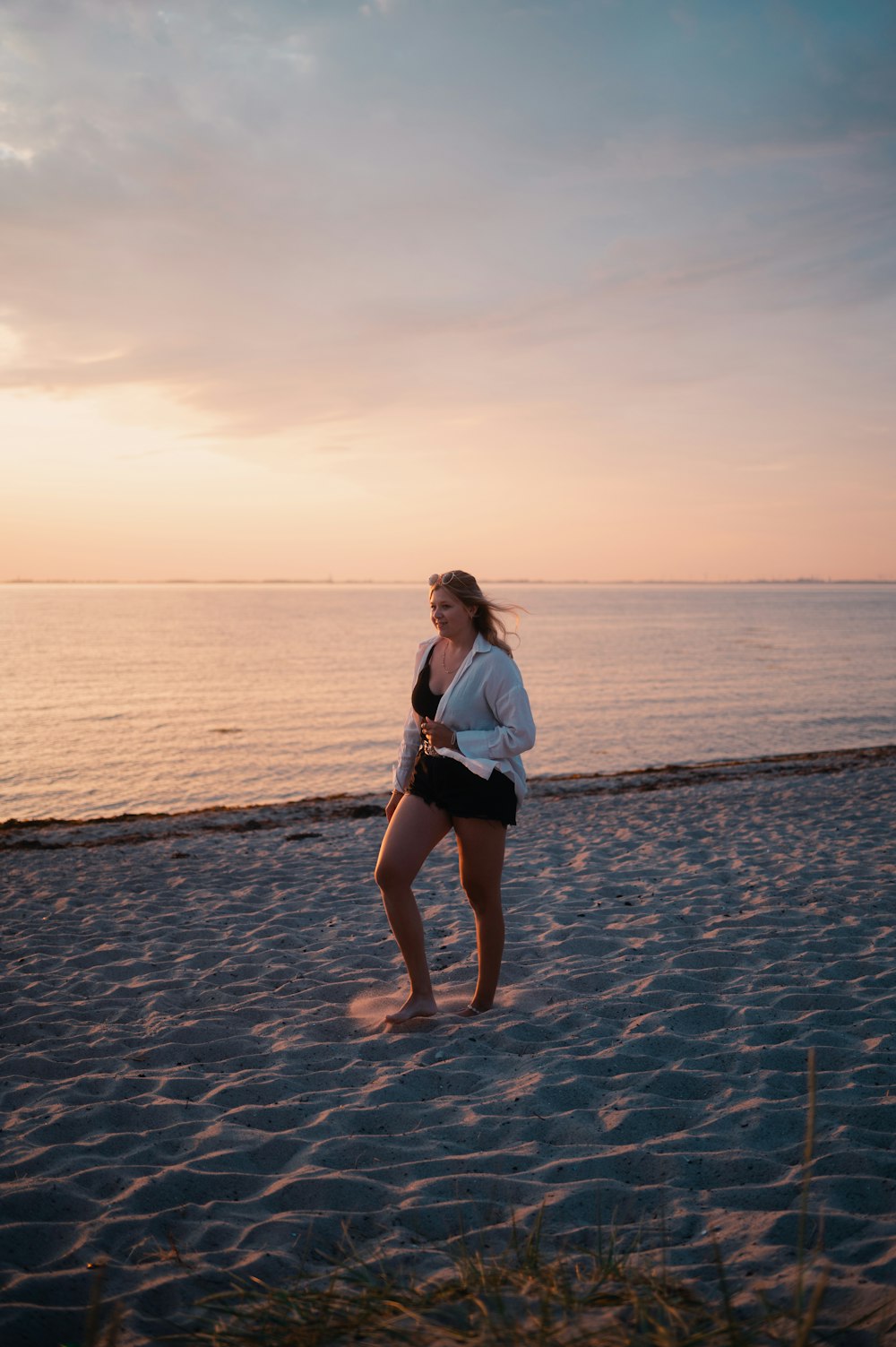 Une femme debout au sommet d’une plage de sable