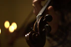 A warm, colorful video thumbnail showing a violin lesson in progress