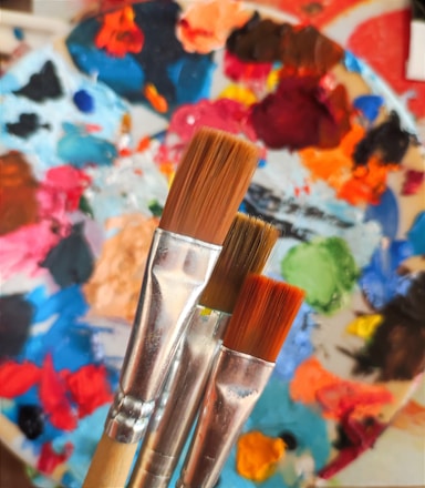 two paintbrushes in front of a colorful background