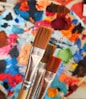 two paintbrushes in front of a colorful background