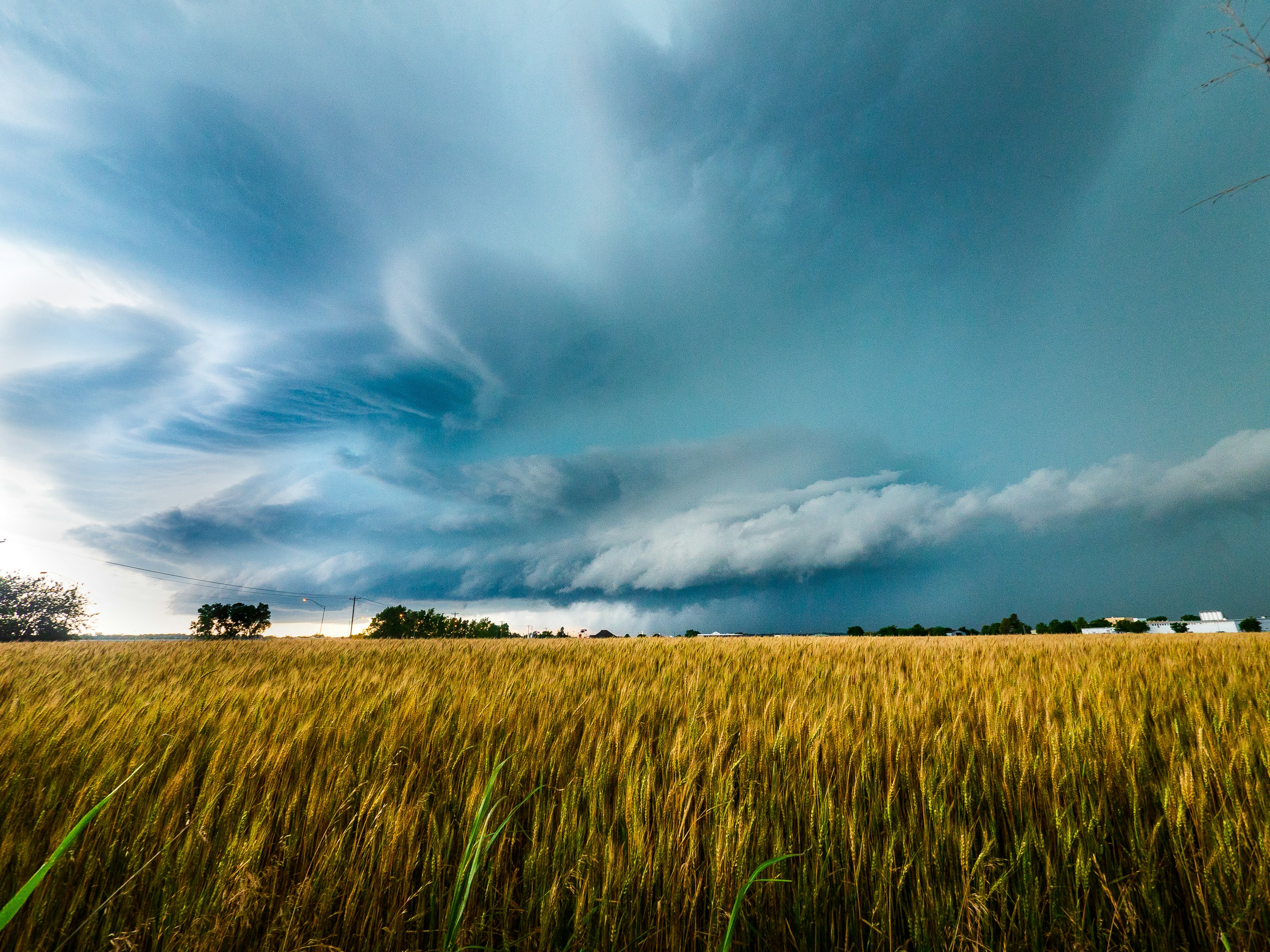 a large field of grass under a cloudy sky, A supercell thunderstorm approaches Pauls Valley, Oklahoma.
