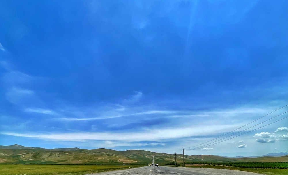 an empty road with a blue sky and mountains in the background