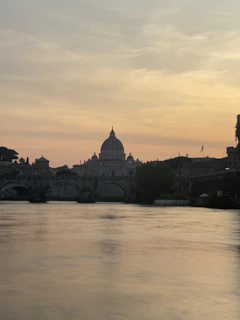A serene view of a historic bridge over a calm river in Prague at sunset.
