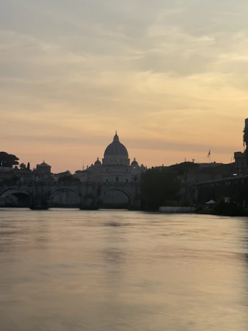 A serene view of a historic bridge over a calm river in Prague at sunset.