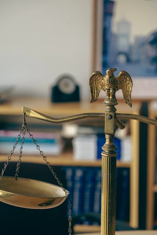 Close-up of legal books and scales on wooden desk.