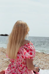 woman sitting on beach next to ocean