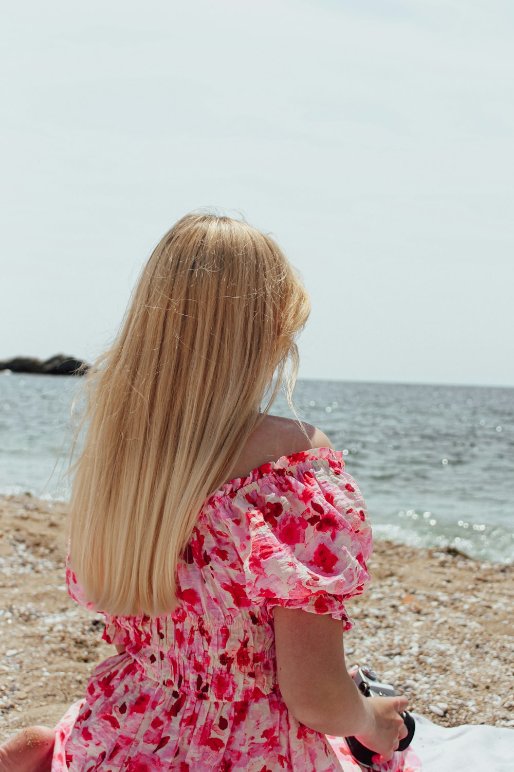 a woman sitting on a beach next to the ocean