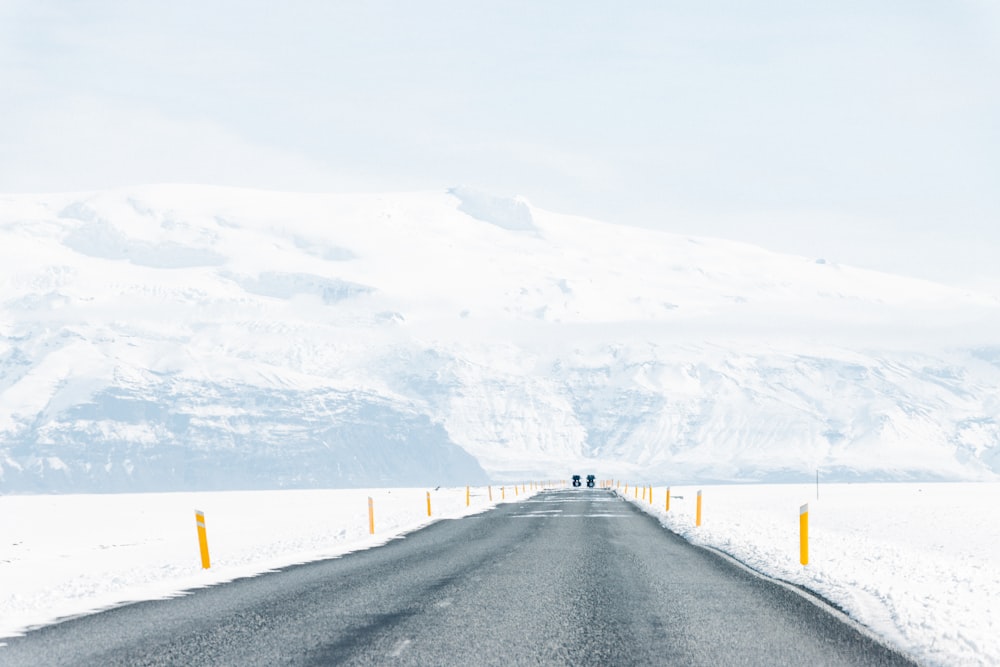 Una lunga strada con una montagna innevata sullo sfondo