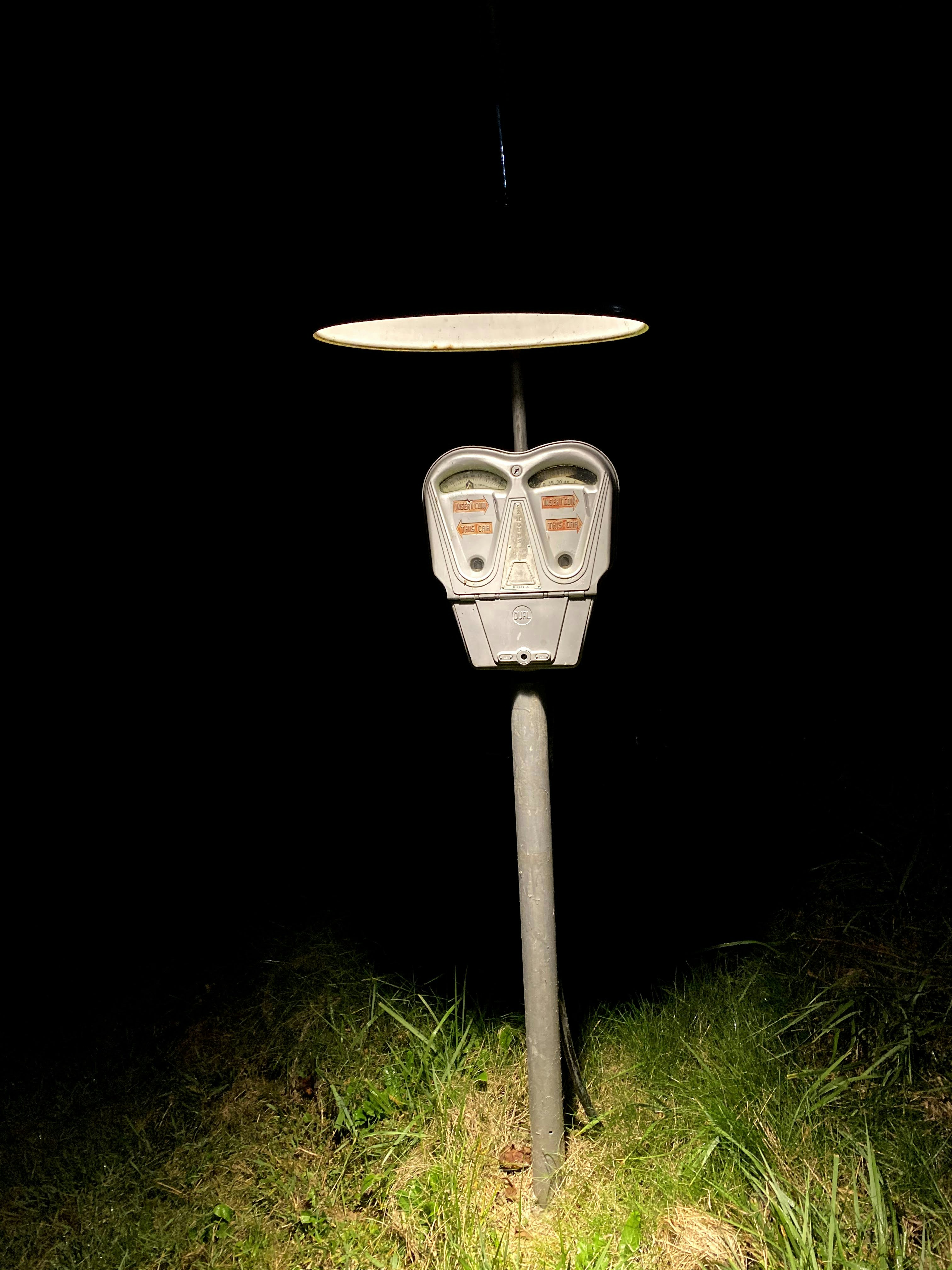 meteran parkir yang duduk di rumput di malam hari
